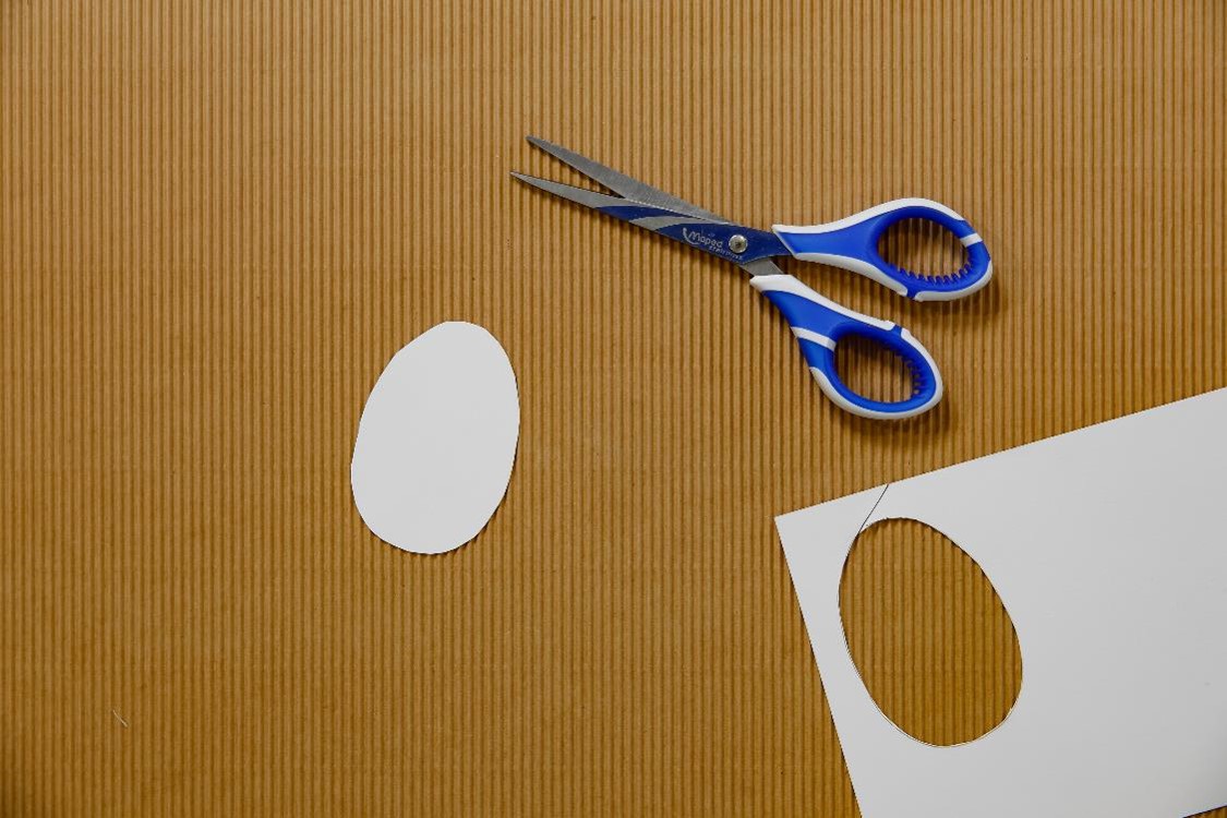 a cut our plain white paper egg next to some scissors