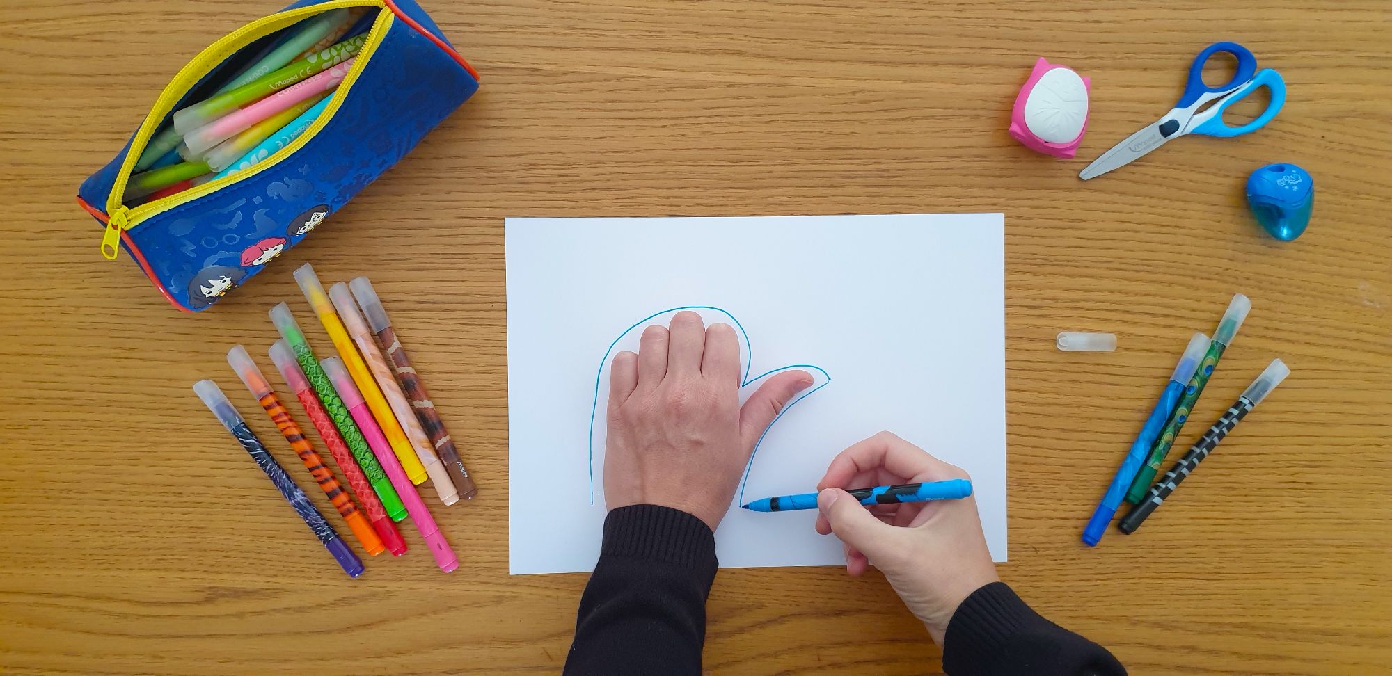 A closed hand placed on a sheet of paper surrounded by stationery