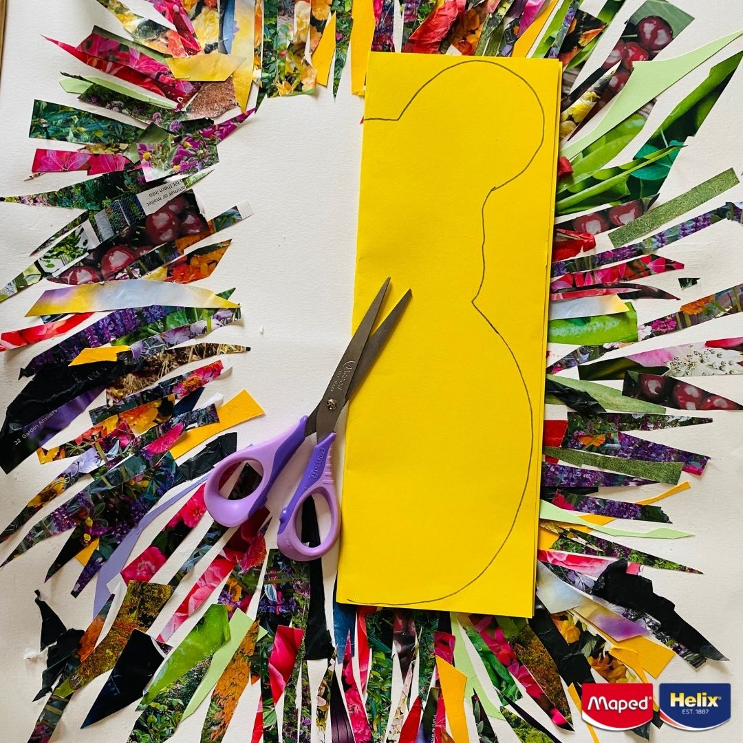 Strips cut from a magazine laying on a piece of paper with coloured paper laying on the top