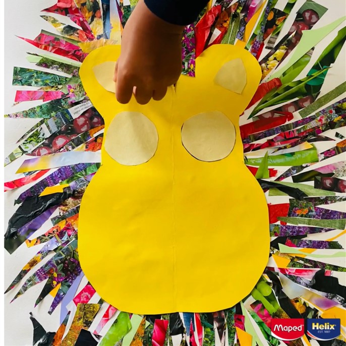 A hand sticking features on a paper lion's face