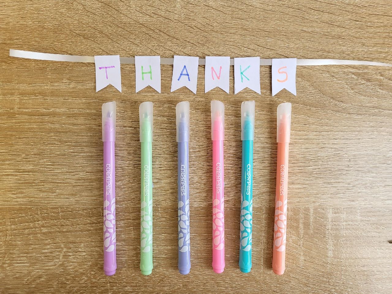 A row of bunting with thanks written on with coloured felt pens underneath each flag