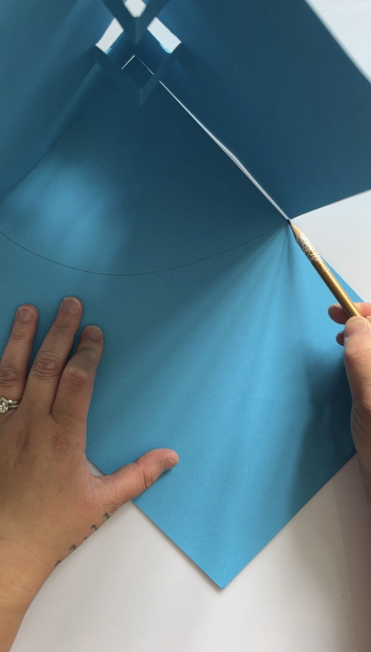 A folded piece of blue paper stood on it's edge on top of another piece of blue paper