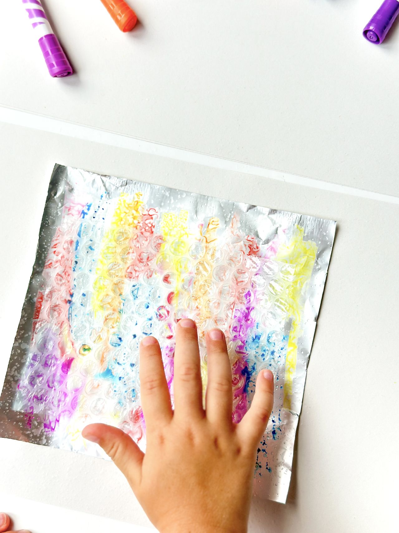 A sheet of bubble wrap laying on top of a sheet of coloured in foil