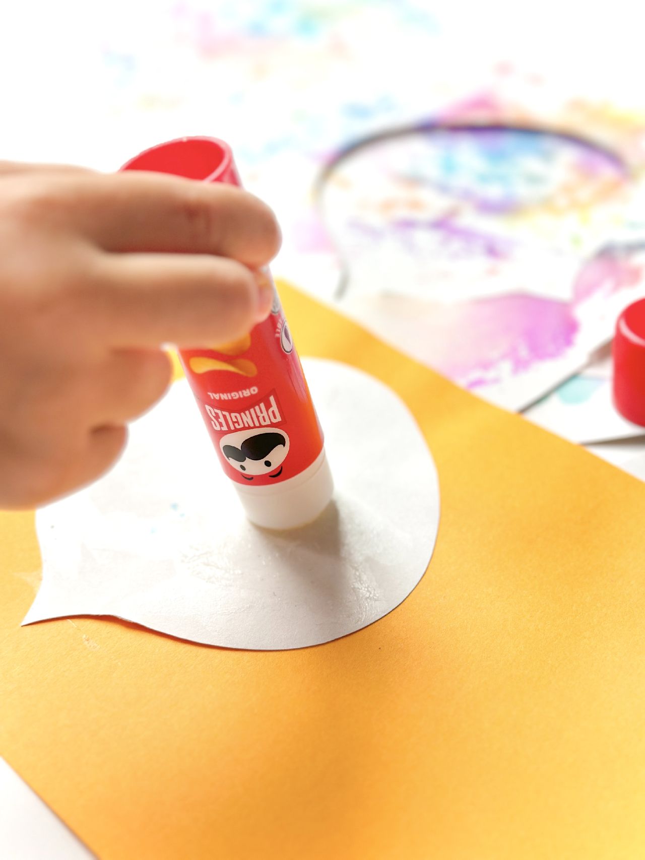 A glue stick with some paper and coloured card