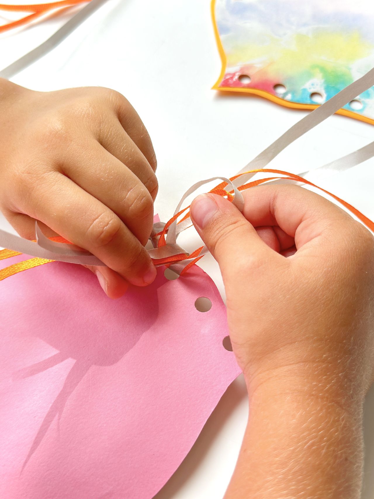 Hands tying ribbon onto a paper octopus